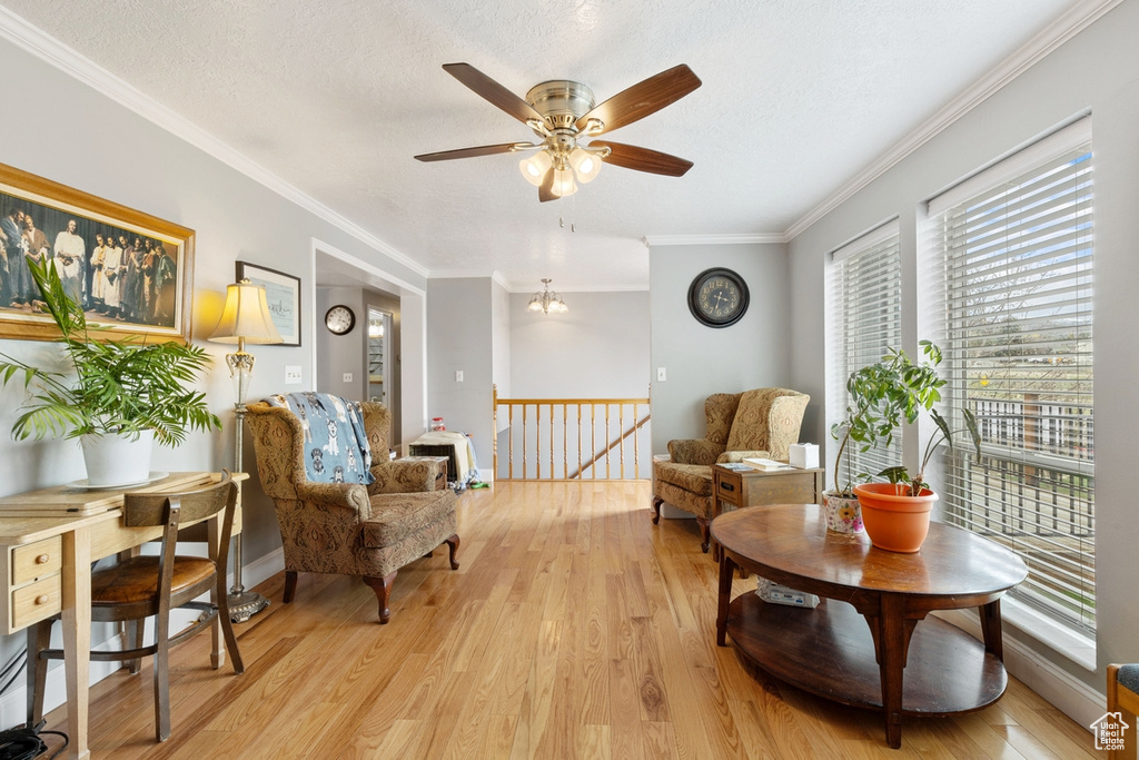 Sitting room featuring an upstairs landing, ceiling fan, light wood-style floors, crown molding, and a textured ceiling