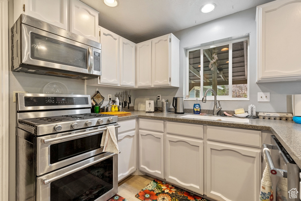 Kitchen featuring appliances with stainless steel finishes, white cabinets, light wood-style floors, and recessed lighting