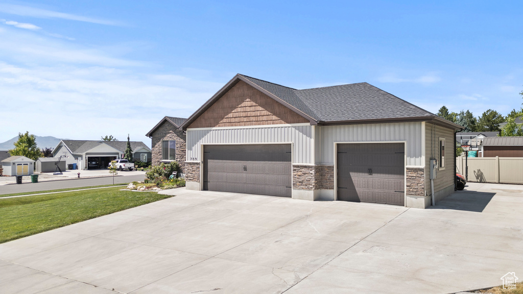 Craftsman-style house with stone siding, concrete driveway, an attached garage, and board and batten siding