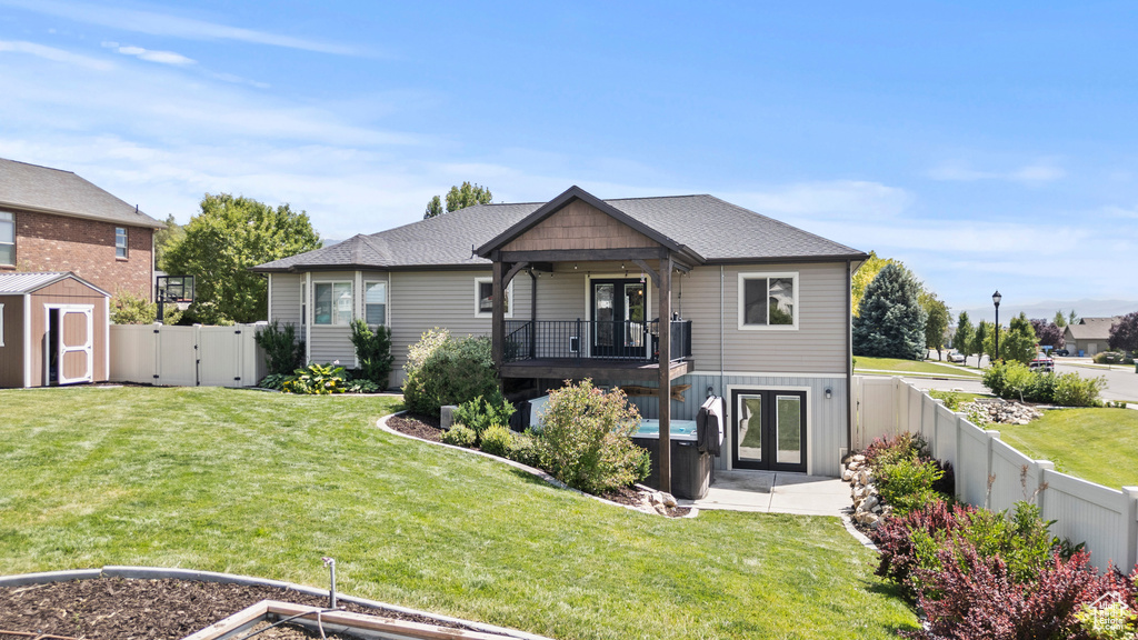 View of front of property with french doors, a fenced backyard, a storage unit, a gate, and a shingled roof