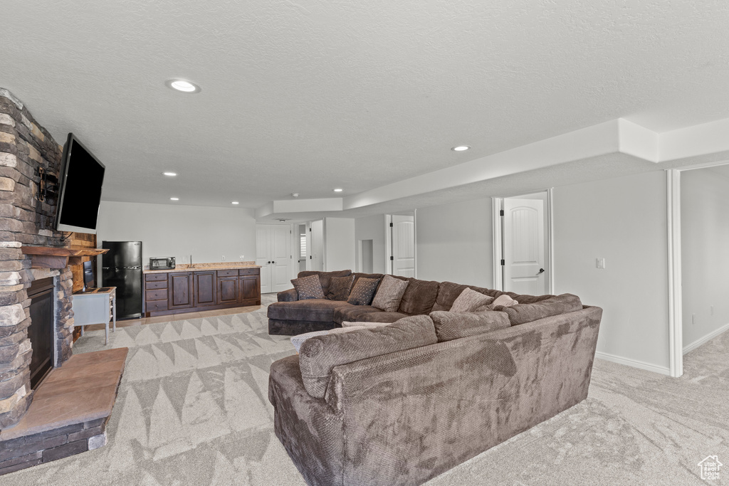 Living room with light colored carpet, a fireplace, recessed lighting, and a textured ceiling