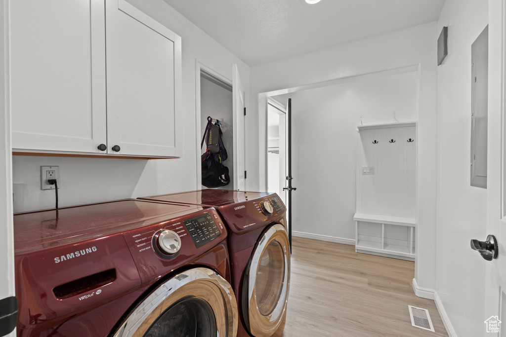 Laundry area with washing machine and clothes dryer, cabinet space, and light wood-style flooring