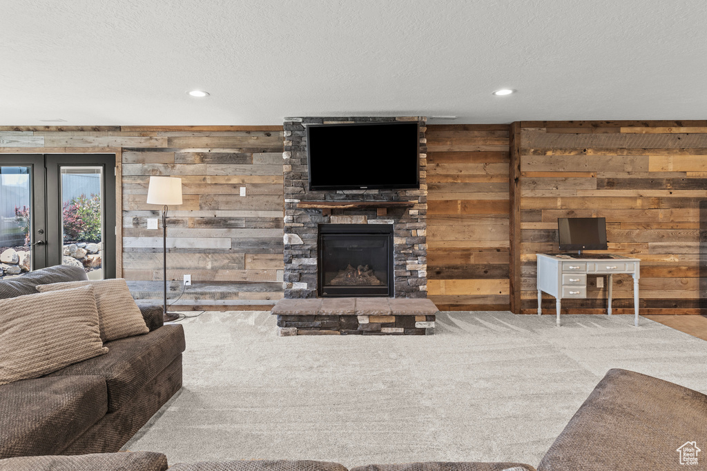 Living area with wood walls, recessed lighting, carpet flooring, a fireplace, and a textured ceiling