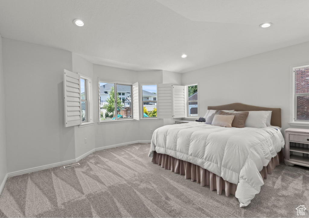 Carpeted bedroom featuring multiple windows and recessed lighting