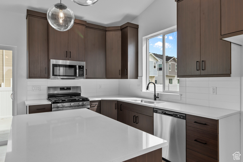 Kitchen featuring stainless steel appliances, decorative backsplash, and light countertops