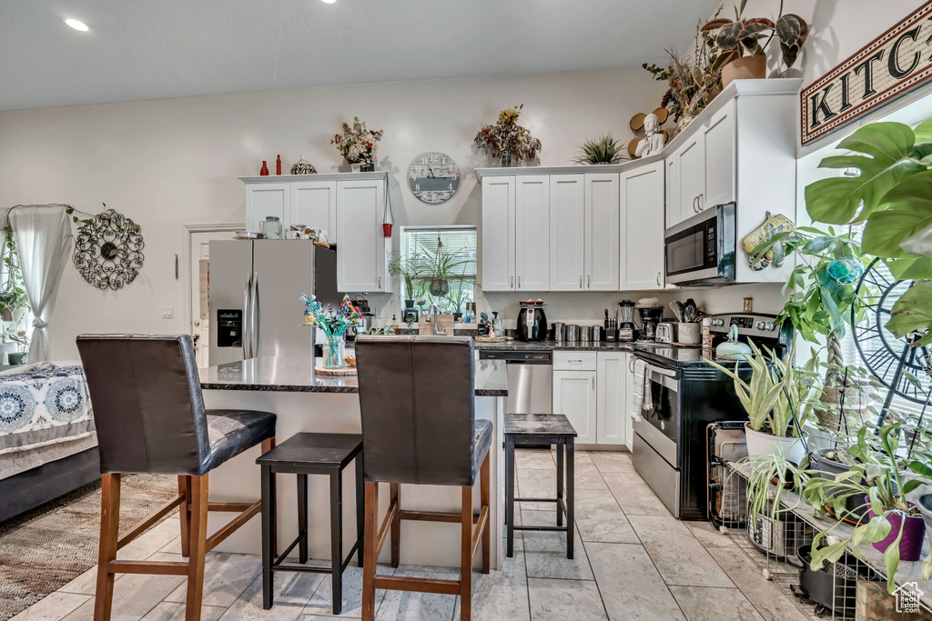 Kitchen featuring appliances with stainless steel finishes, a kitchen bar, white cabinetry, a center island, and recessed lighting