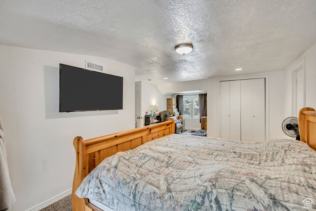 Carpeted bedroom featuring a textured ceiling, a closet, and recessed lighting