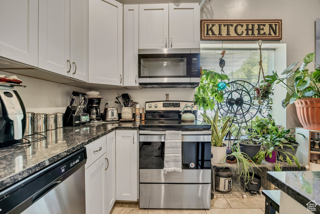 Kitchen featuring stainless steel appliances, white cabinets, and dark stone countertops