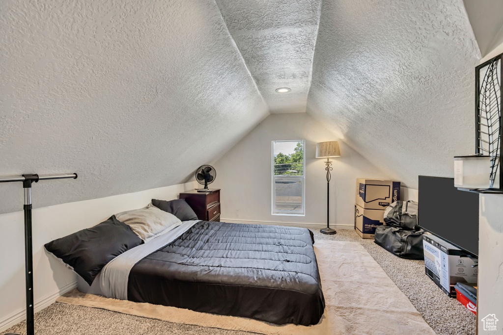 Carpeted bedroom featuring a textured ceiling and lofted ceiling