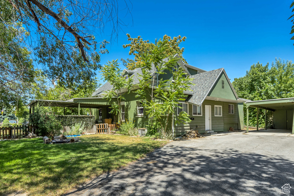 Farmhouse-style home featuring a shingled roof, asphalt driveway, and a carport