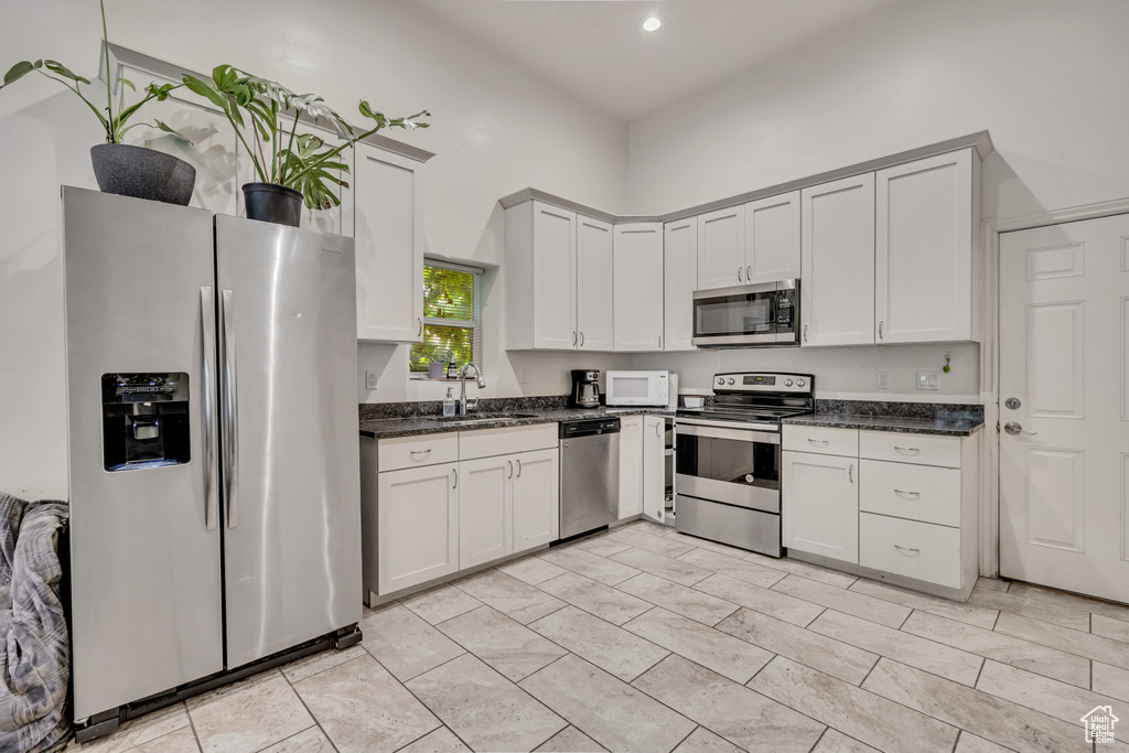 Kitchen with appliances with stainless steel finishes, dark stone counters, and recessed lighting