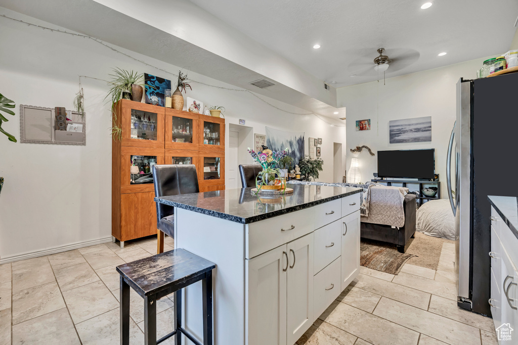 Kitchen featuring freestanding refrigerator, ceiling fan, a kitchen breakfast bar, white cabinets, and open floor plan