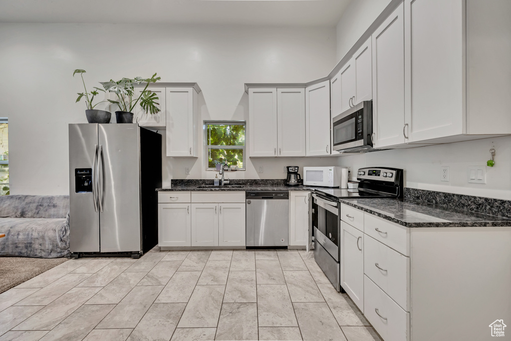 Kitchen featuring stainless steel appliances, dark stone counters, and white cabinetry