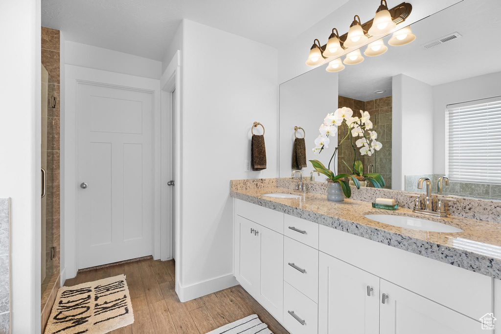 Bathroom featuring double vanity, a stall shower, and wood finished floors