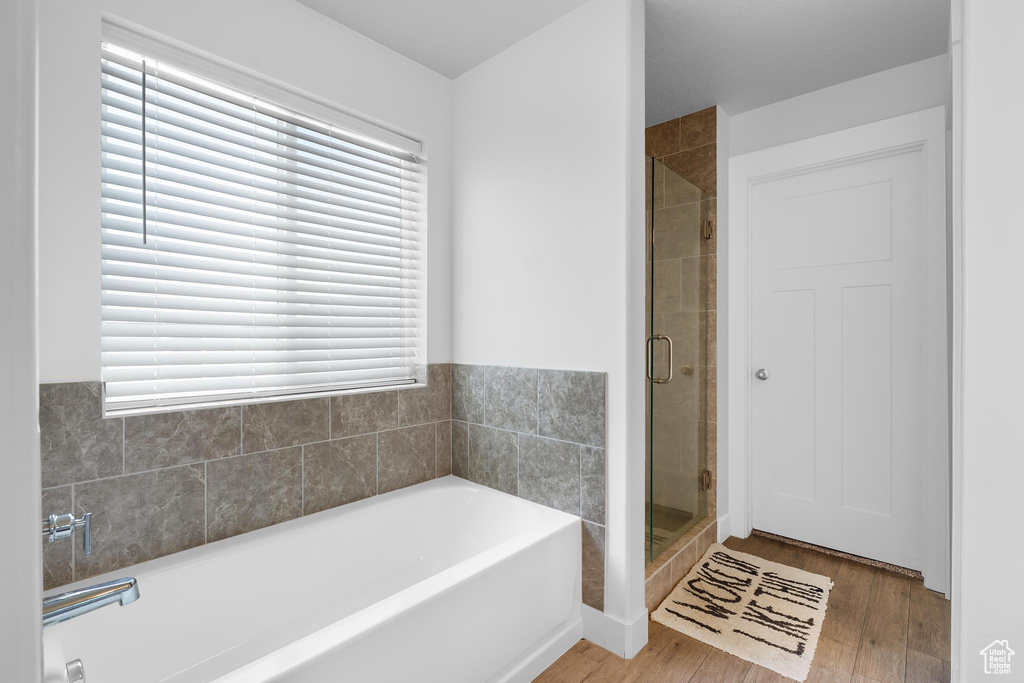 Full bath with a bath, a shower stall, wood finished floors, and plenty of natural light
