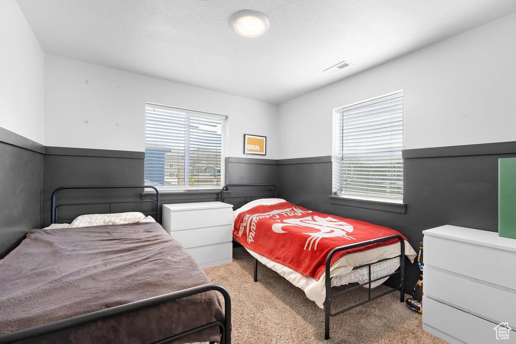 Carpeted bedroom featuring a wainscoted wall