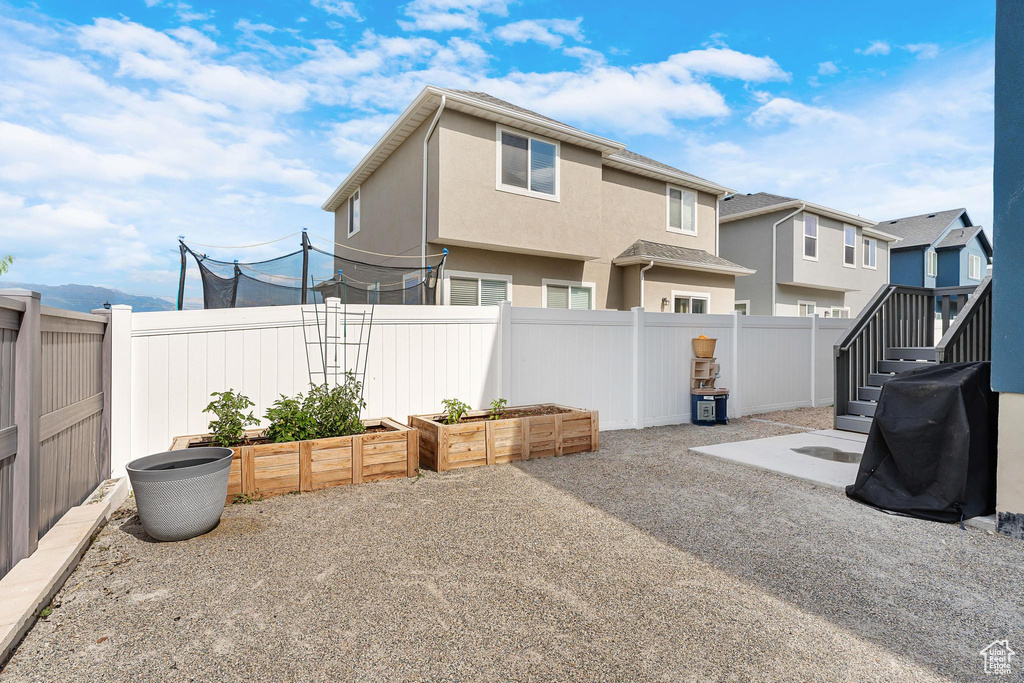 Fenced backyard featuring a vegetable garden and a residential view
