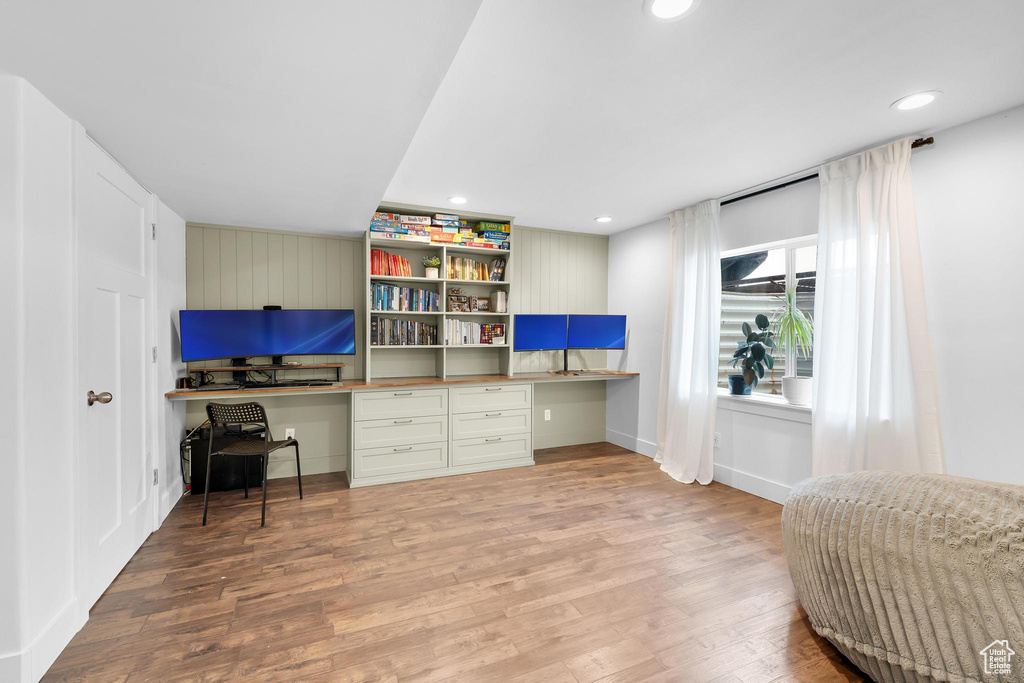 Office featuring built in desk, wood finished floors, and recessed lighting