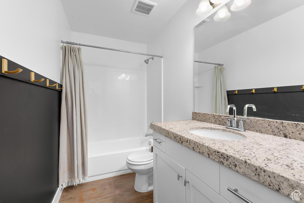 Bathroom featuring vanity, shower / bath combo, and wood finished floors