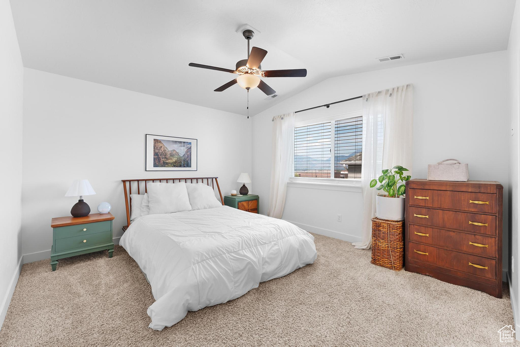 Carpeted bedroom featuring vaulted ceiling and ceiling fan