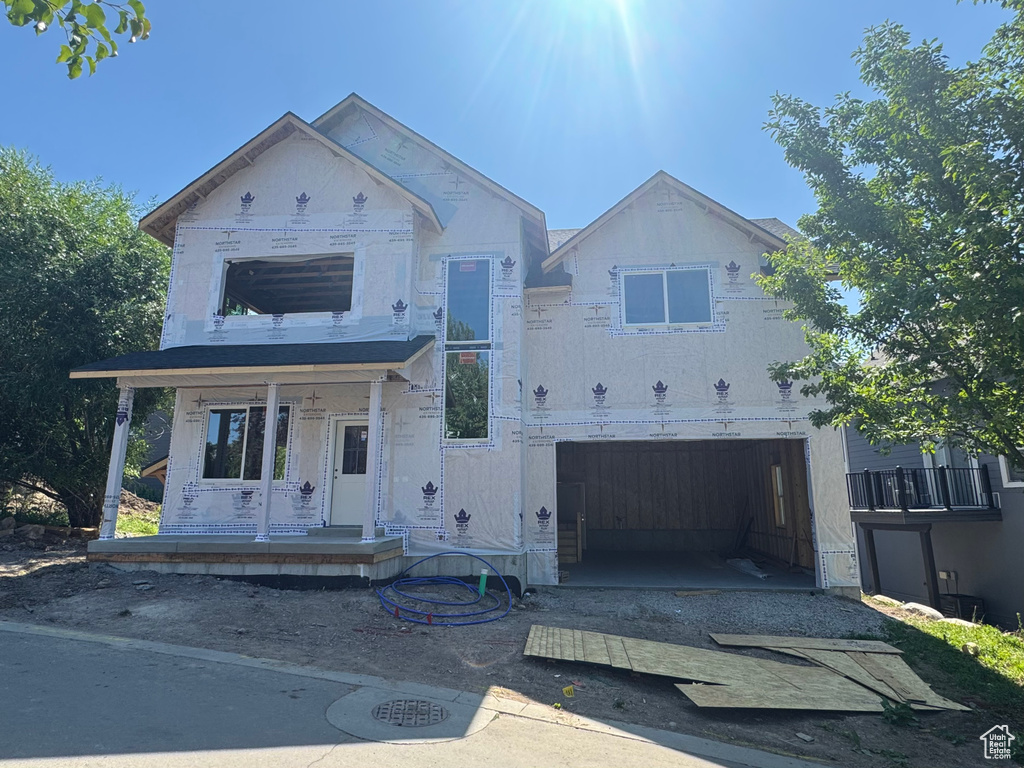 Property in mid-construction with dirt driveway, an attached garage, and covered porch