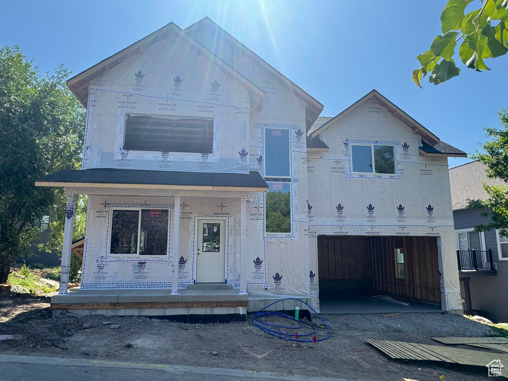 Unfinished property featuring an attached garage, driveway, and a porch
