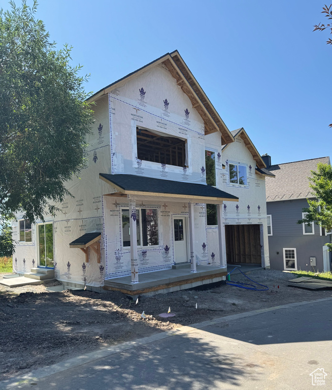 Unfinished property featuring a garage, covered porch, and dirt driveway