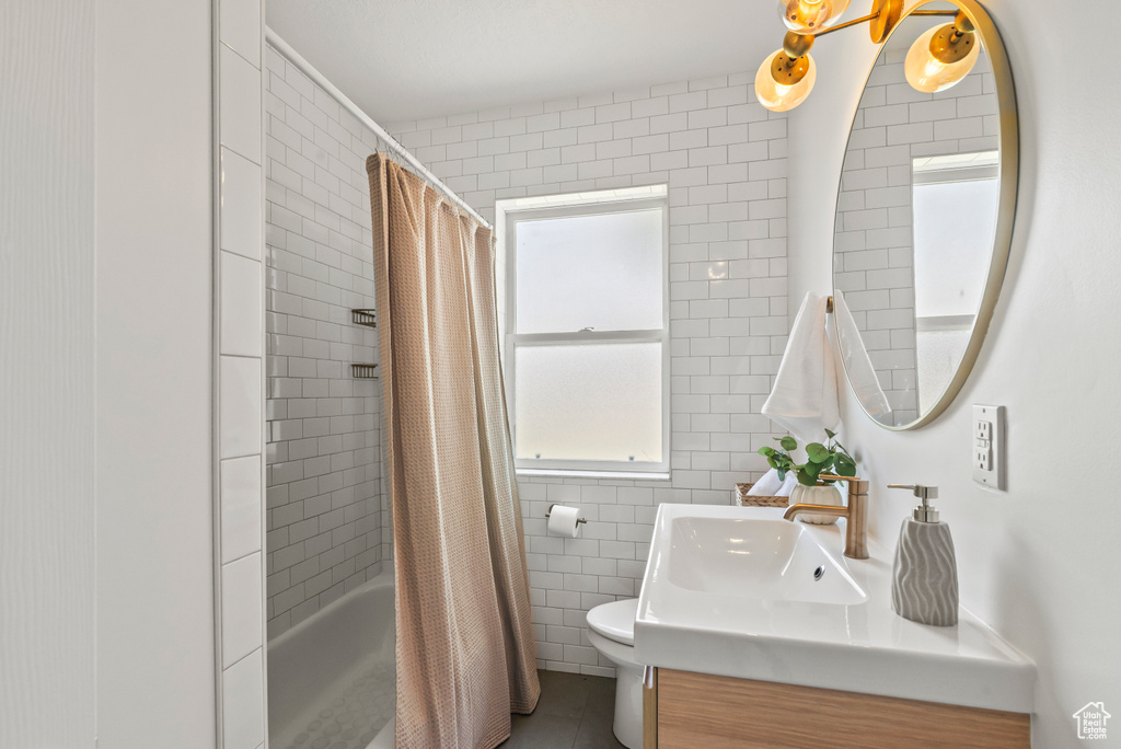 Full bath with vanity, shower / bath combo with shower curtain, tile walls, and tile patterned floors