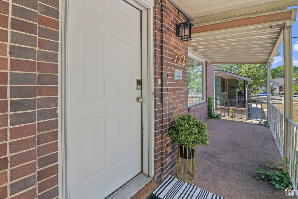 Property entrance featuring brick siding and a porch
