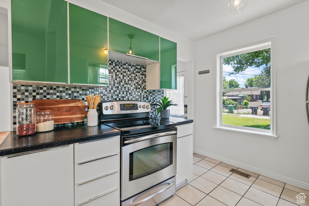 Kitchen featuring electric range, tasteful backsplash, light tile patterned floors, and white cabinets