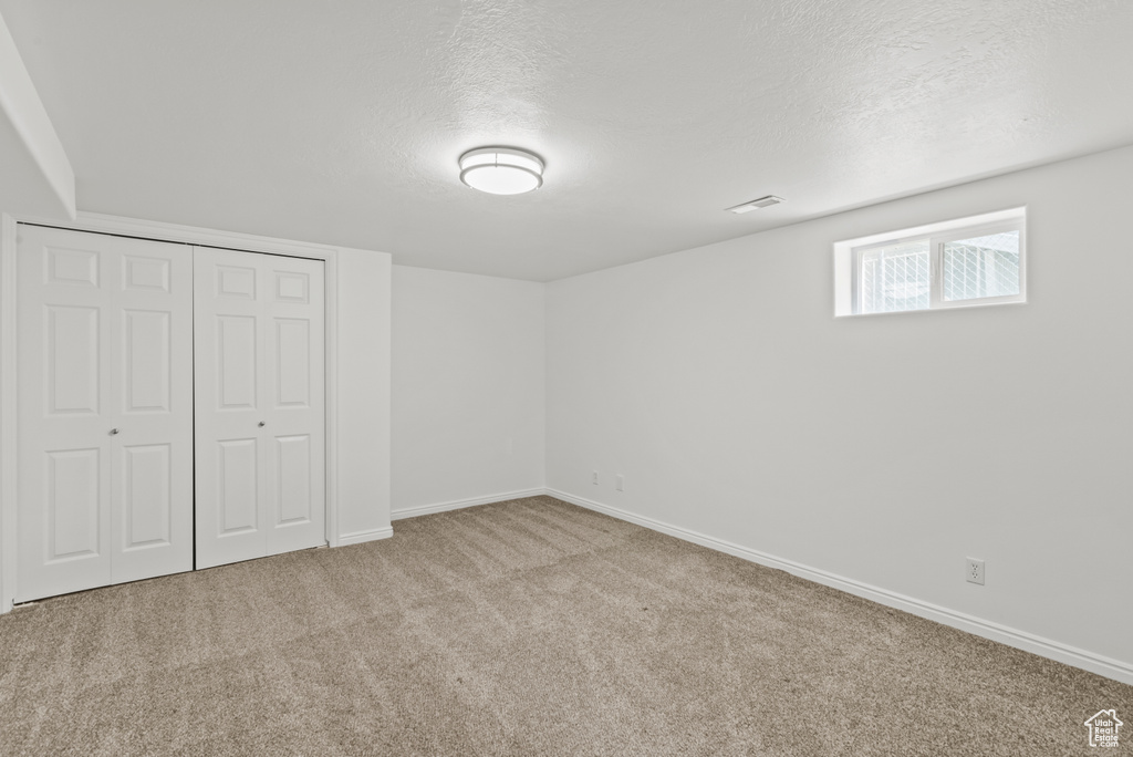 Unfurnished bedroom featuring carpet, a closet, and a textured ceiling