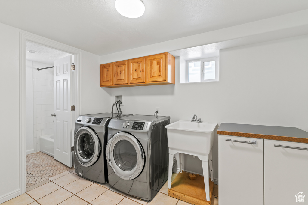 Laundry room featuring separate washer and dryer, cabinet space, and light tile patterned floors