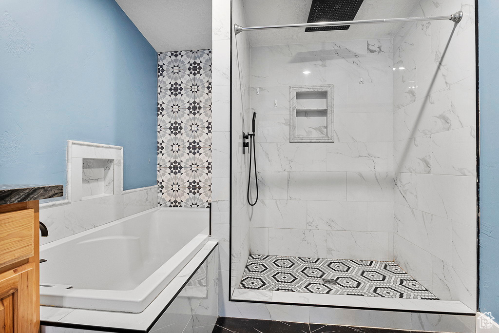 Bathroom featuring a bath and a marble finish shower