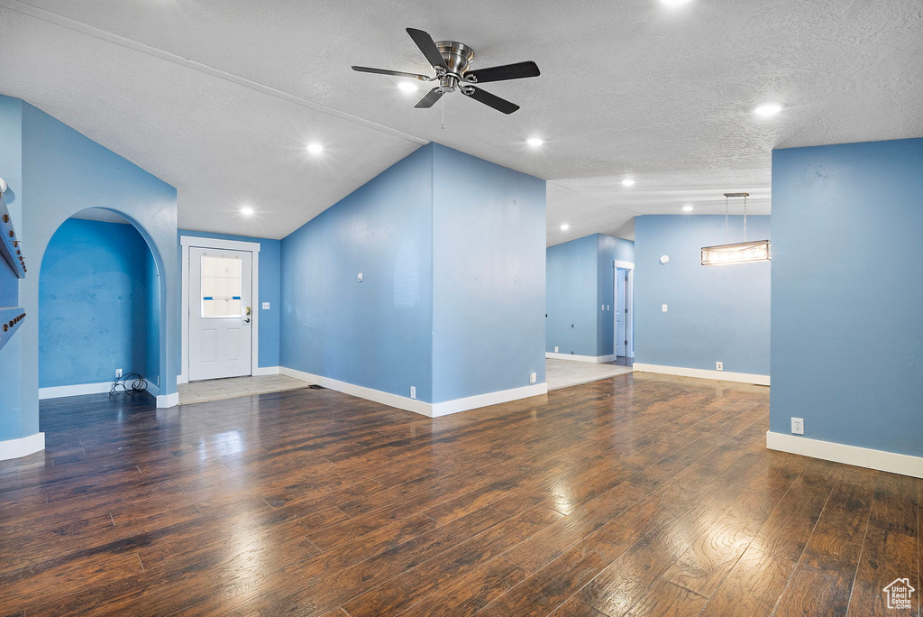 Unfurnished living room with arched walkways, a ceiling fan, lofted ceiling, wood finished floors, and recessed lighting