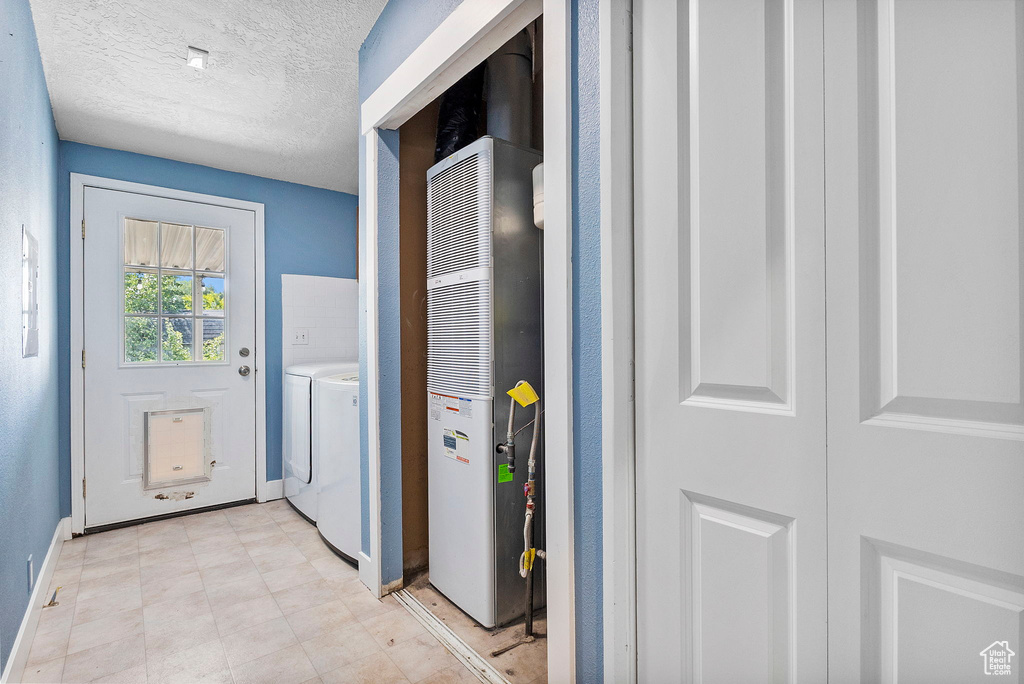 Laundry room featuring a heating unit, washer / clothes dryer, and a textured ceiling