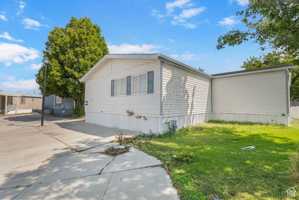View of side of home with a lawn and a patio