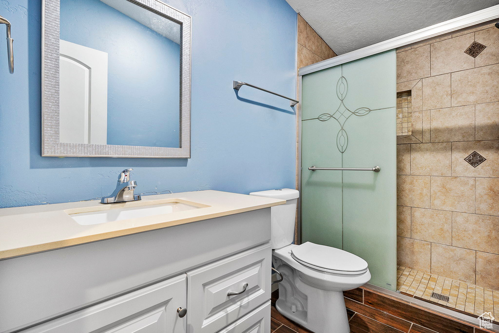 Bathroom featuring vanity, a shower stall, wood finished floors, and a textured ceiling