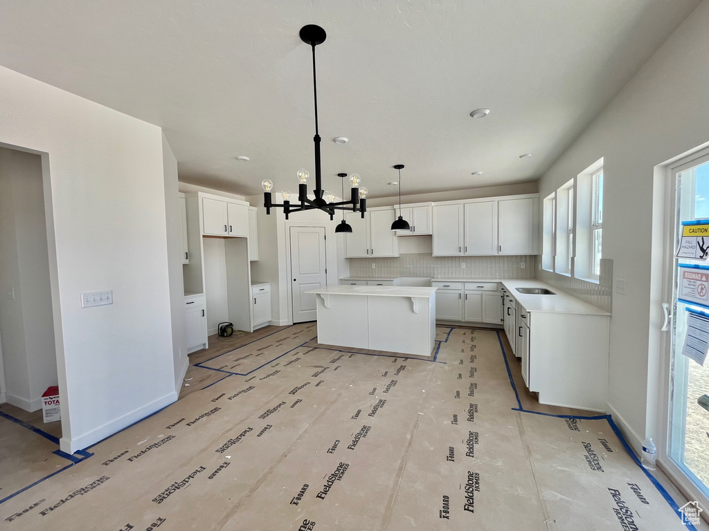Kitchen with a kitchen island, healthy amount of natural light, a chandelier, and decorative backsplash