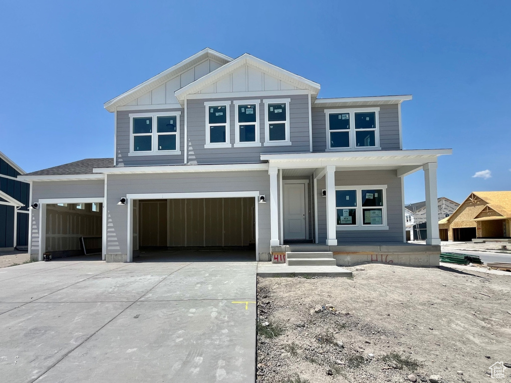 View of front of house featuring covered porch, driveway, board and batten siding, and an attached garage