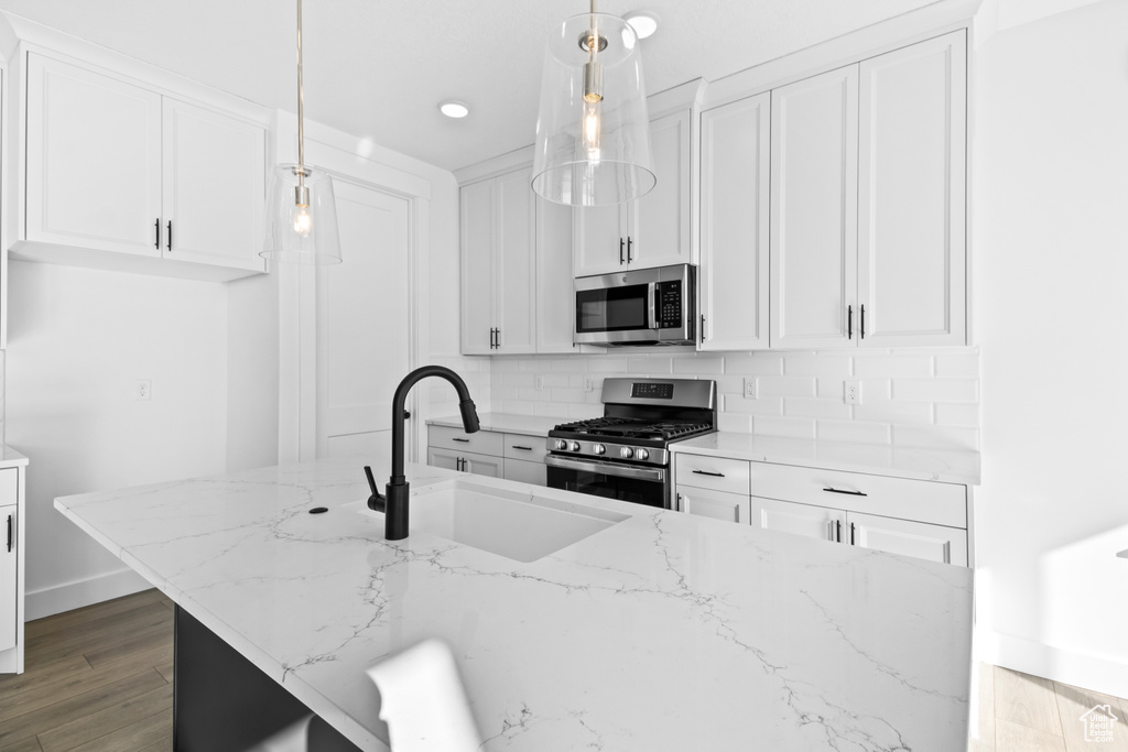 Kitchen with appliances with stainless steel finishes, tasteful backsplash, white cabinetry, light stone counters, and recessed lighting