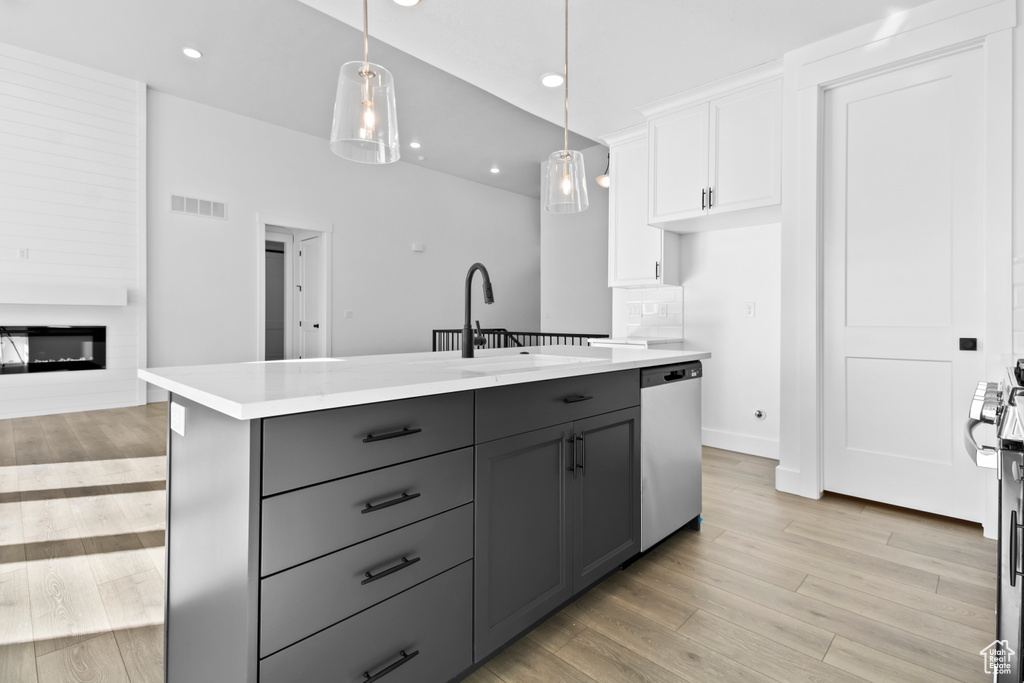 Kitchen featuring dishwasher, gray cabinets, white cabinetry, light wood finished floors, and light countertops