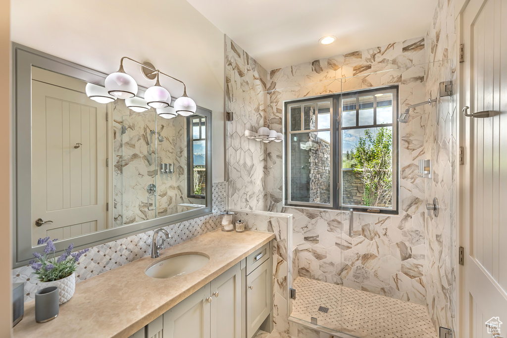 Full bathroom with a marble finish shower, vanity, and healthy amount of natural light