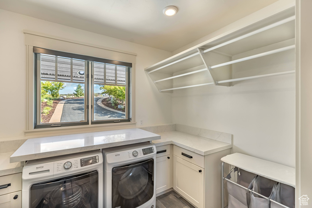 Laundry area featuring washing machine and dryer, cabinet space, and dark wood-type flooring