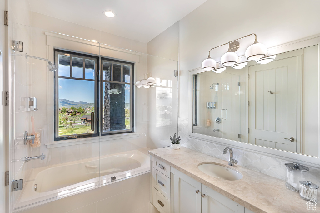 Bathroom with a bath, vanity, a shower with shower door, healthy amount of natural light, and recessed lighting