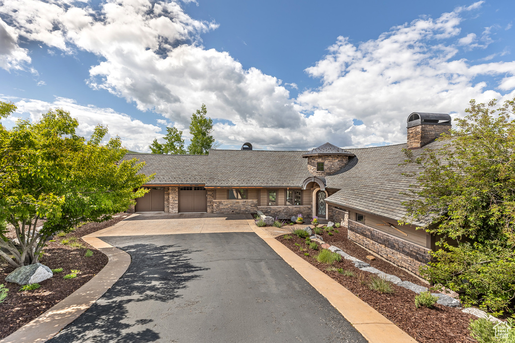 View of front of home with stone siding, driveway, and a garage