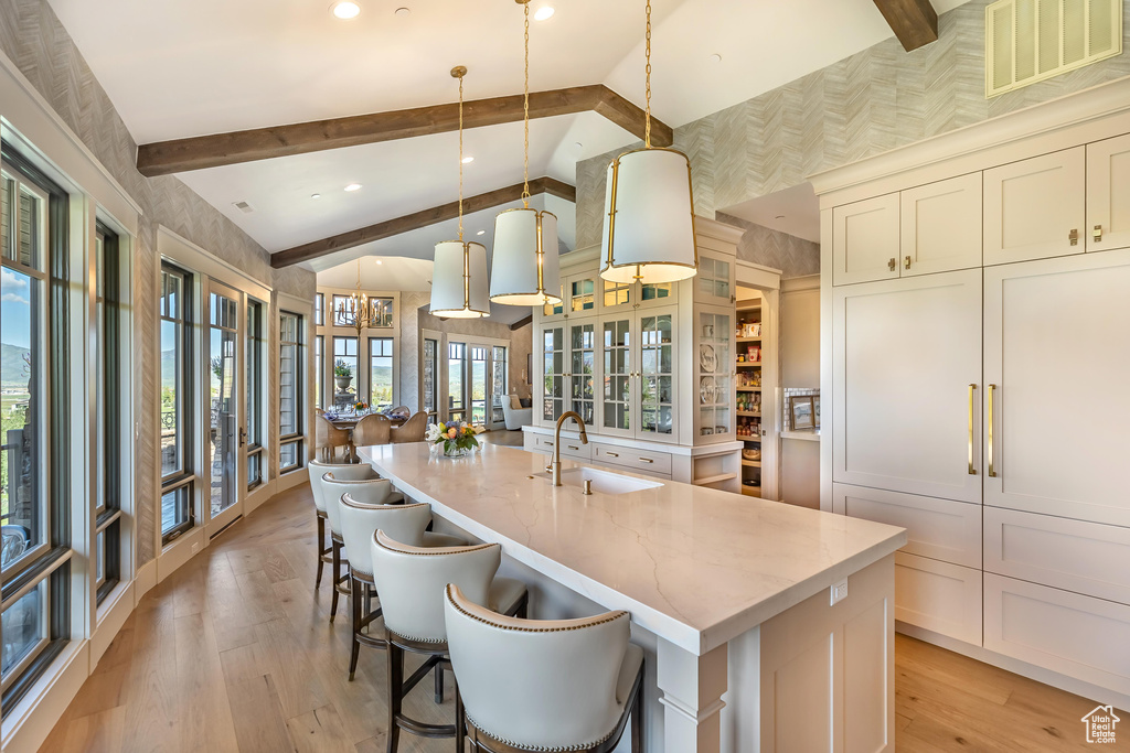 Kitchen featuring an island with sink, light wood-style floors, pendant lighting, light countertops, and recessed lighting