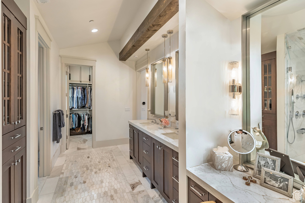 Bathroom featuring double vanity, a shower, a walk in closet, and vaulted ceiling