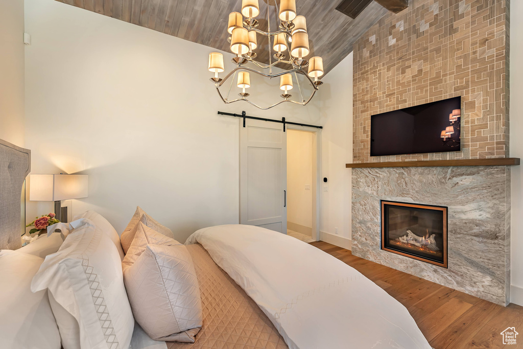 Bedroom featuring a barn door, wood finished floors, lofted ceiling, a chandelier, and wooden ceiling