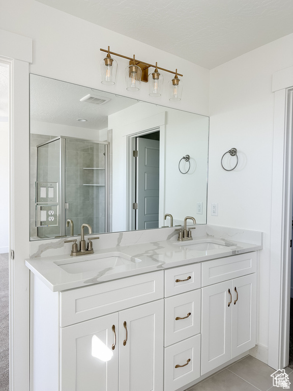 Bathroom featuring double vanity, tile patterned floors, and a shower stall