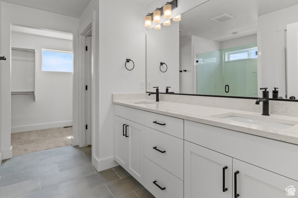 Full bathroom with double vanity, healthy amount of natural light, and a shower stall